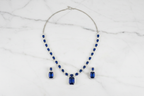 Royal blue sapphire AD tennis necklace set flat lay on white marble