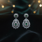 Emerald chandelier drop earrings on black velvet editorial flat lay