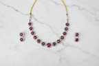 Ruby round halo AD necklace set flat lay on white marble