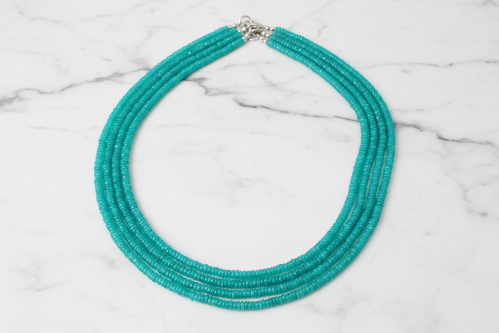 Flat lay of turquoise rondelle bead necklace on white marble