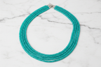 Flat lay of turquoise rondelle bead necklace on white marble
