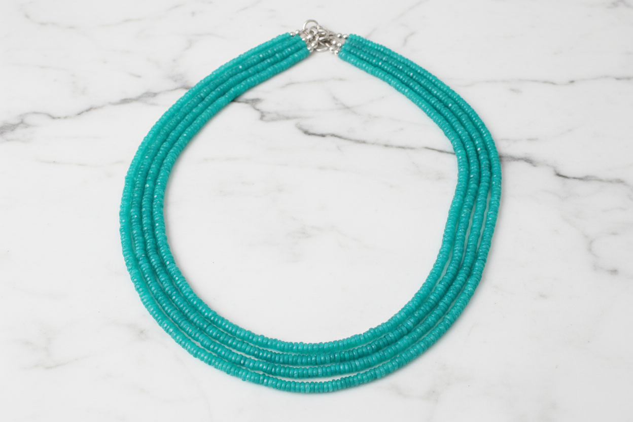 Flat lay of turquoise rondelle bead necklace on white marble