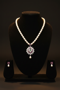 Pearl and emerald AD floral pendant necklace set with earrings on dark velvet studio display