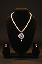 Pearl and emerald AD floral pendant necklace set with earrings on dark velvet studio display