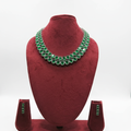 Emerald green oval AD double-row tennis necklace set with linear stud earrings on burgundy velvet display