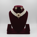 Multi-strand seed pearl choker with ruby and emerald floral centrepiece set on burgundy velvet display