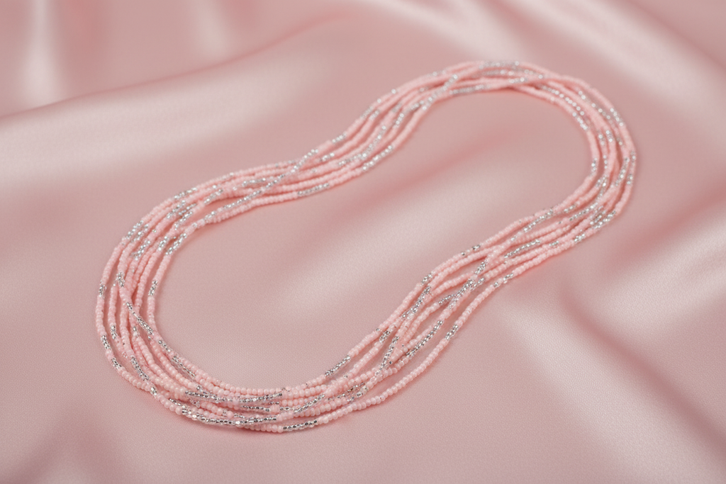 Flat lay of pink and silver seed bead necklace on blush pink silk