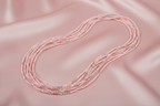 Flat lay of pink and silver seed bead necklace on blush pink silk