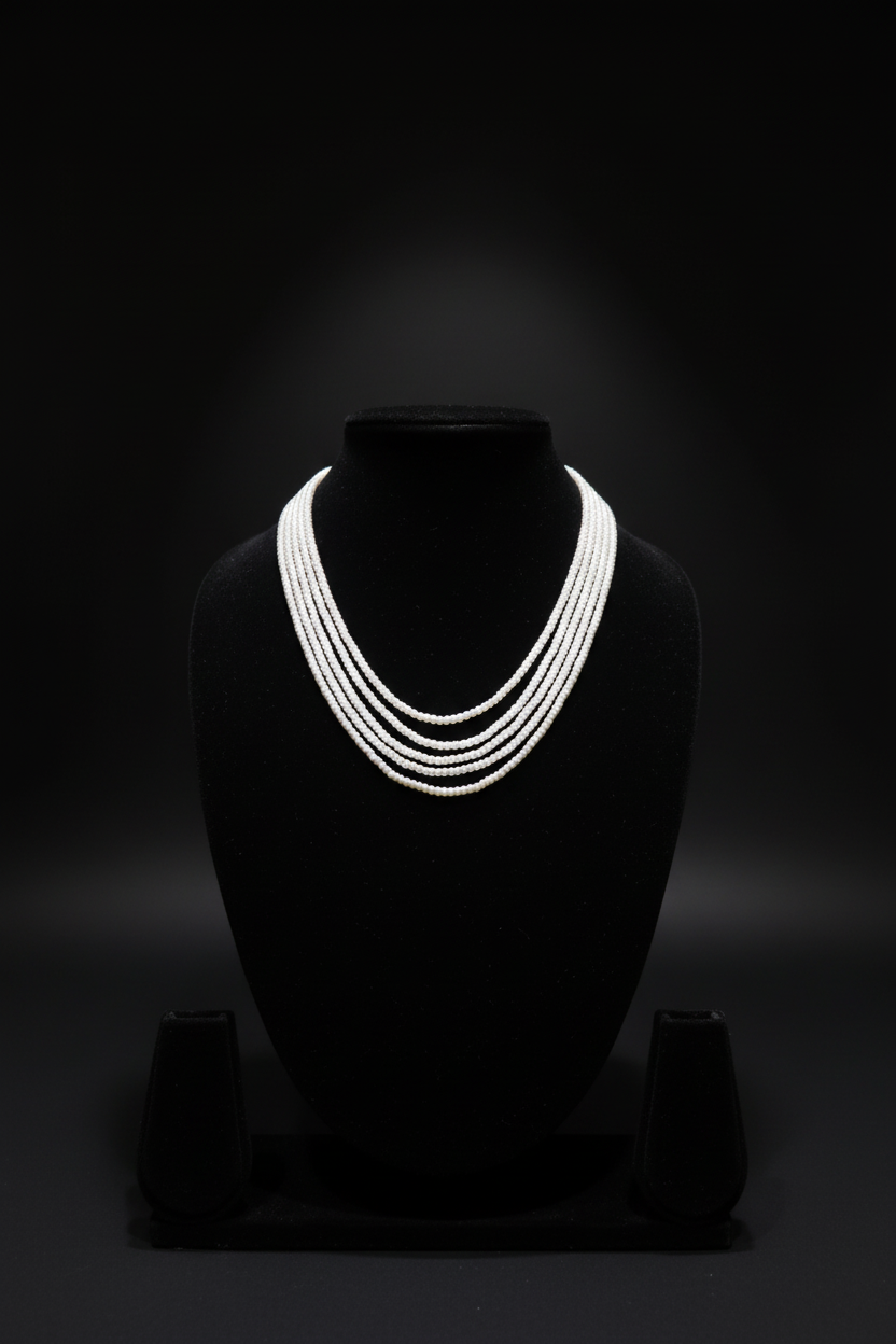 4-strand layered white seed pearl necklace on dark velvet studio display