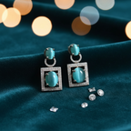 Teal cat's eye drop earrings on dark velvet editorial flat lay
