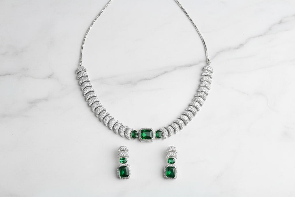 Emerald triple-stone AD pave disc necklace set flat lay on white marble