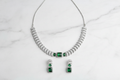 Emerald triple-stone AD pave disc necklace set flat lay on white marble