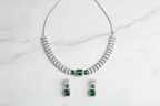 Emerald triple-stone AD pave disc necklace set flat lay on white marble