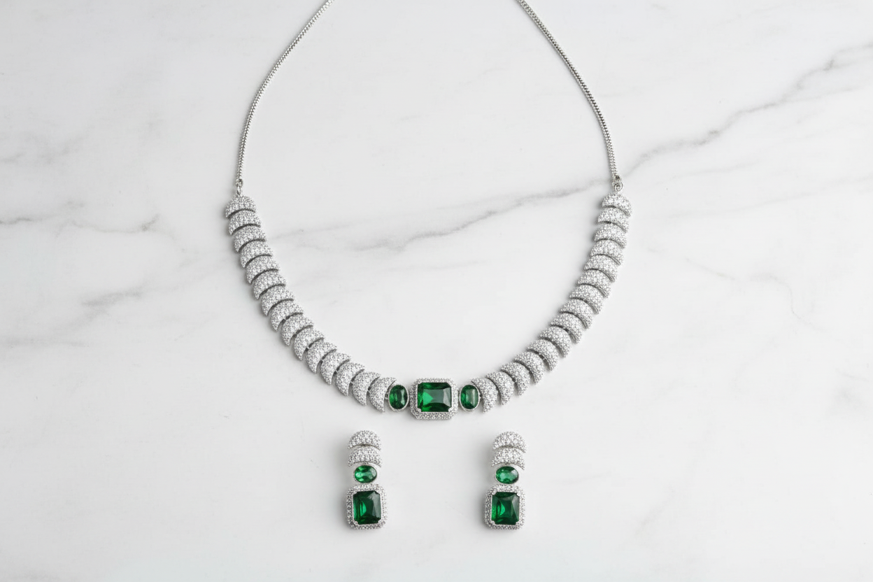 Emerald triple-stone AD pave disc necklace set flat lay on white marble