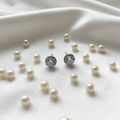 White CZ round cluster halo stud earrings on white silk with pearls - lifestyle style