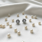 White CZ round cluster halo stud earrings on white silk with pearls - lifestyle style