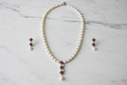 Flat lay of pearl and emerald AD floral pendant necklace set with earrings on white marble