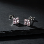 Blush pink CZ princess cut square stud earrings on dark charcoal slate - moody editorial style