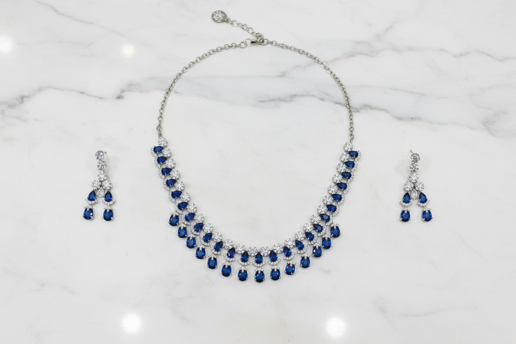 Sapphire blue AD double-row fringe necklace set flat lay on white marble