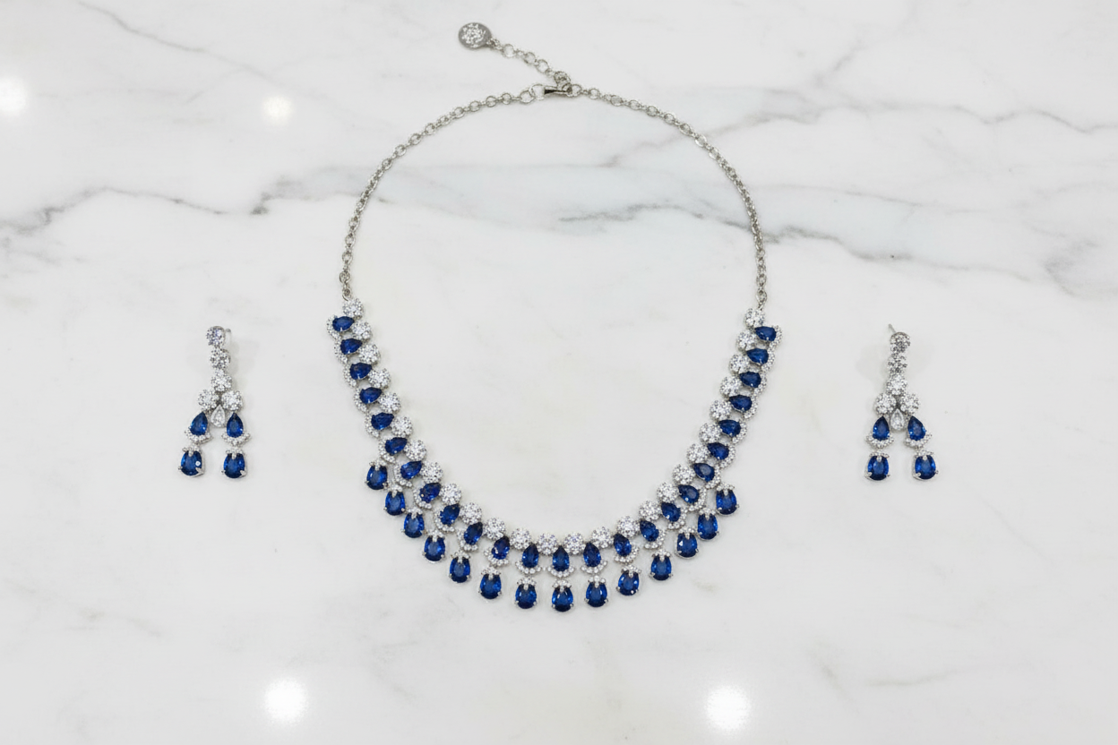 Sapphire blue AD double-row fringe necklace set flat lay on white marble