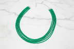 Flat lay of emerald green crystal bead necklace on white marble