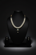 White AD necklace with teal pendant and pearl drop set on dark velvet studio display
