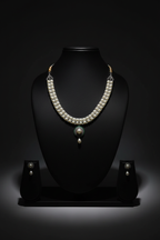 White AD necklace with teal pendant and pearl drop set on dark velvet studio display