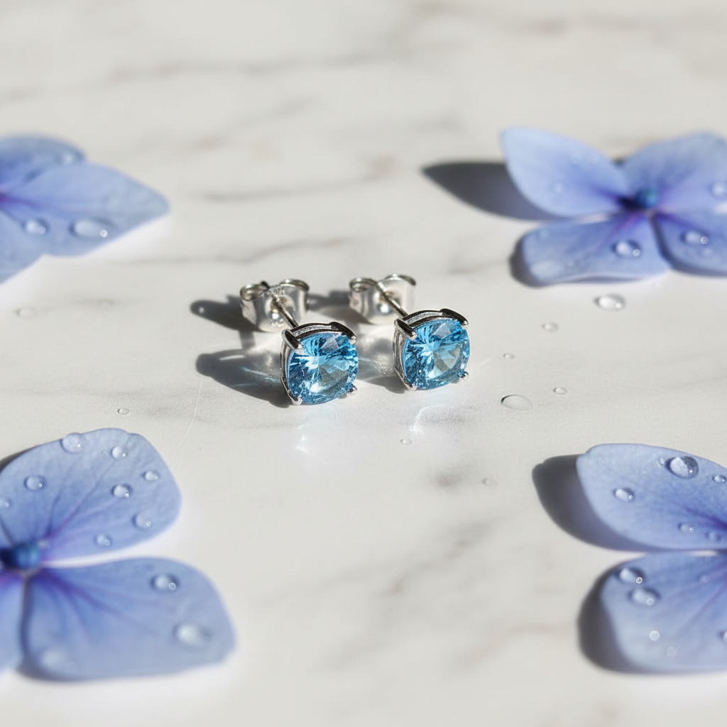 Sky blue topaz CZ round cushion stud earrings on white marble with hydrangea petals - lifestyle style